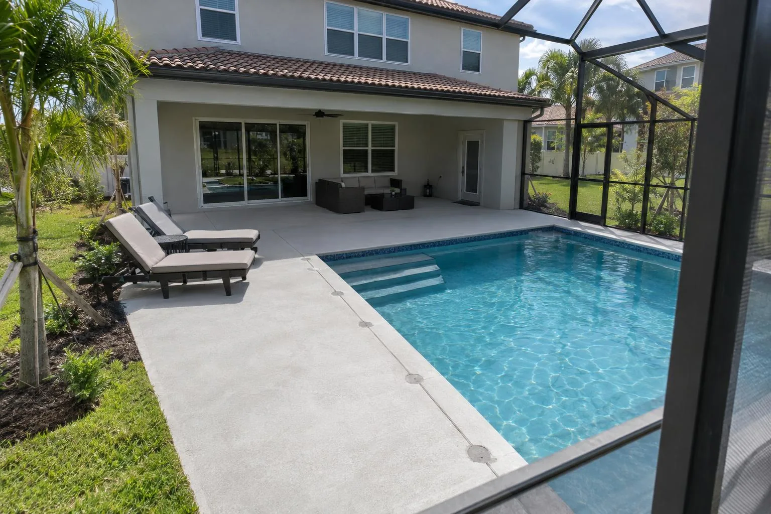 A level concrete pool deck beside a screened pool